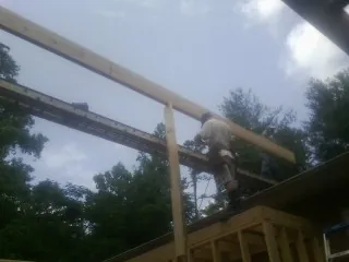 Carpenter setting a ridge beam over a new addition frame — Ice Dam Removal by Roofing Brothers in Schneider
