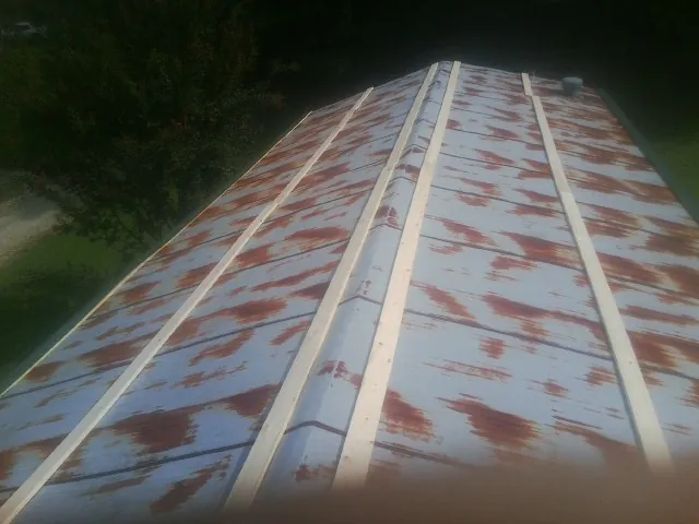 Rusted metal roof panels with new wood purlins before replacement — Storm Damage Roof Repair in Schneider by Roofing Brothers