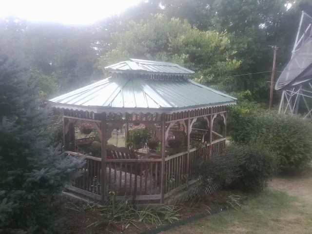 Green metal roof on a backyard gazebo surrounded by garden beds in Schneider