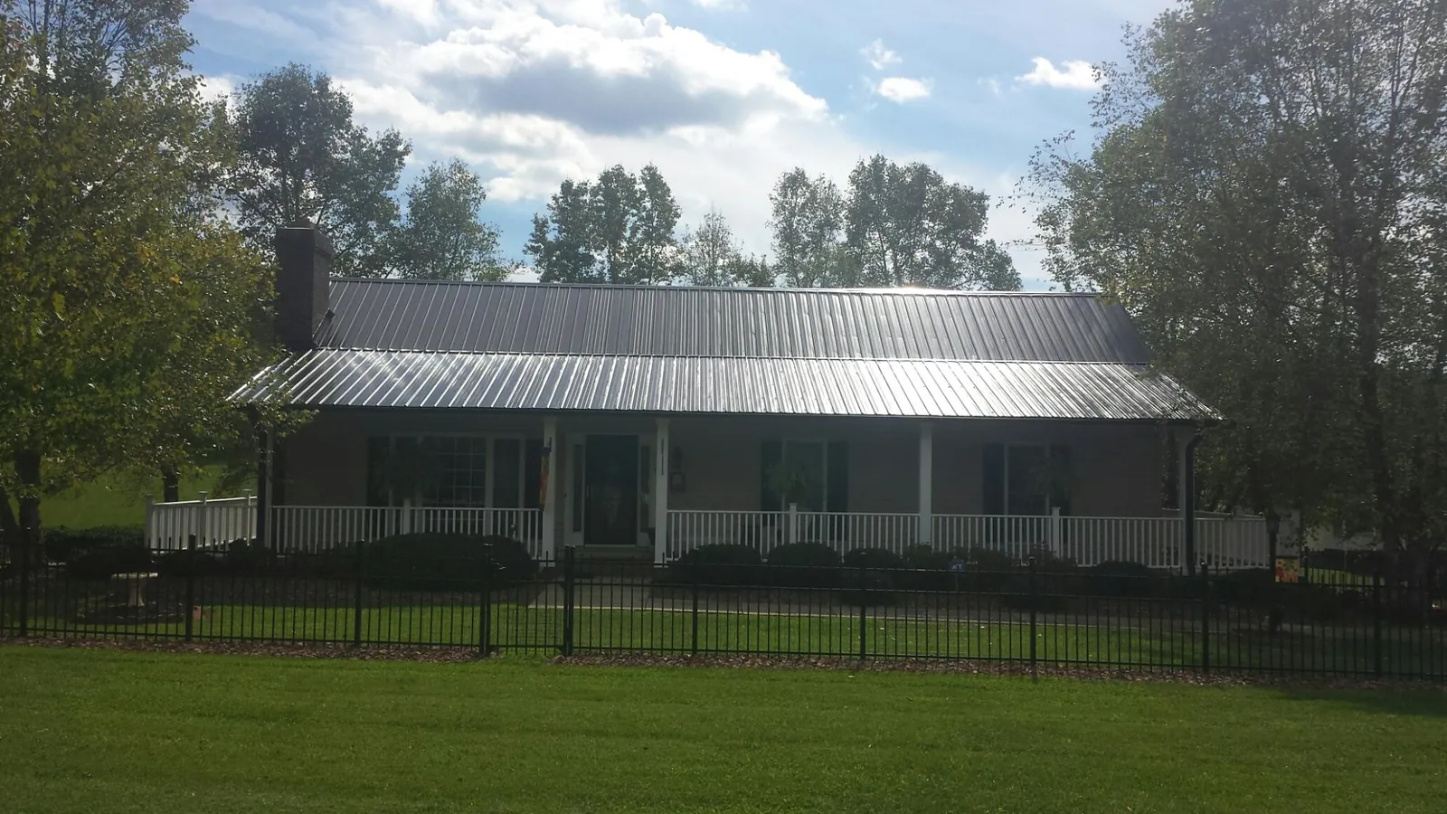 Gray metal roof on a brick ranch with a full width front porch — Gutter Guard Installation work by our crew in Schneider