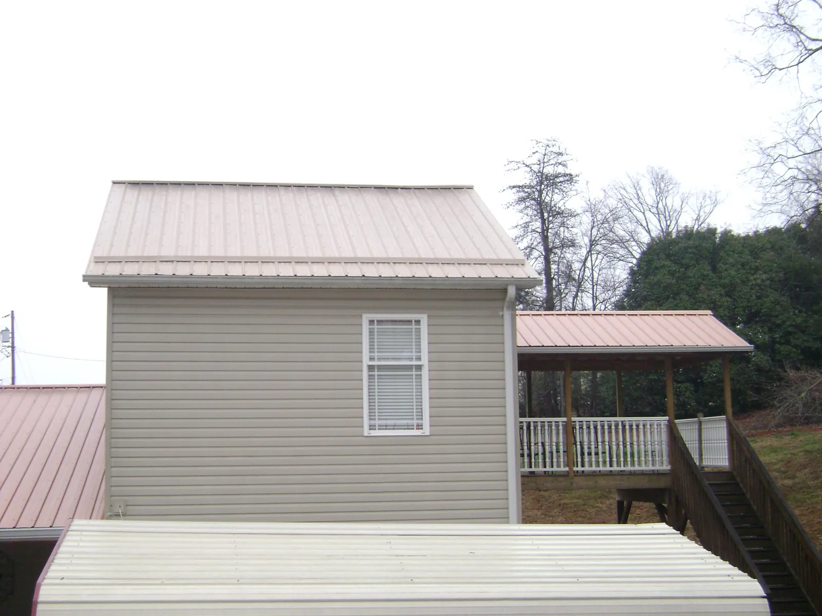 Tan metal roofs on a two story addition and attached porch, from a Roof Replacement job in Schneider
